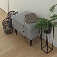 Tapicerowana ławeczka z obiciem w kolorze szarym.