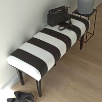 Elegancka ławka w paski z czarnymi nogami.